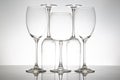 A minimalist display of five empty wine glasses with slender stems, their reflections creating symmetry on a glossy table against Royalty Free Stock Photo