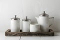 Minimalist elegance with sleek white cylinders and silver lids on rustic tray