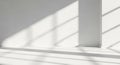 Minimalist empty white room with bright natural sunlight casting geometric window shadows on textured wall and floor Royalty Free Stock Photo