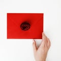 Minimalist fashion and beauty photo. A love letter in a red envelope with a rose. Female hands lay a love letter. The Royalty Free Stock Photo