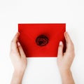 Minimalist fashion and beauty photo. A love letter in a red envelope with a rose. Female hands lay a love letter. The Royalty Free Stock Photo