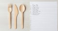 Wooden cutlery and handwritten recipe notes on a light wooden table surface Royalty Free Stock Photo