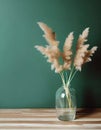 Minimalist glass vase of dried grasses on a green background.