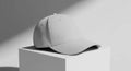 Minimalist Grey Baseball Cap on White Pedestal with Dramatic Shadows Royalty Free Stock Photo