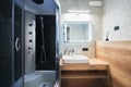 Minimalist grey bathroom with shower cabin and white sink on wooden countertop.