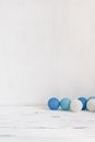 Minimalist home decor. Blue balls garland on a white wooden table, shabby backdrop. Minimal still life. Christmas concept