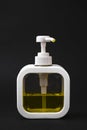 A minimalist image of a plastic dispenser bottle with a yellow liquid on a black background. Royalty Free Stock Photo