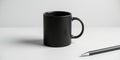 A minimalist image showing a black ceramic mug and a pen on a white surface in soft lighting Royalty Free Stock Photo