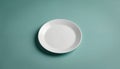 Minimalist image of single white ceramic plate centered on solid teal background. Clean, simple design features subtle lighting, Royalty Free Stock Photo
