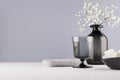 Minimalist interior bathroom in monochrome grey color - black glass vase with small white flowers, goblet, silver cosmetic bag. Royalty Free Stock Photo