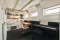 Spacious study room with table, shelves and piano Royalty Free Stock Photo