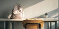 Minimalist and inviting study space featuring a light backpack, open book, and small plant on a wooden desk, illuminated by Royalty Free Stock Photo