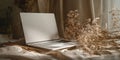 Minimalist laptop setup on a draped fabric surface with dried flowers, natural light, ideal for remote work or creative projects. Royalty Free Stock Photo