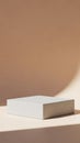 Minimalist light grey rectangular concrete block or podium casting a soft shadow on a warm beige surface under diffused lighting Royalty Free Stock Photo