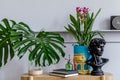 Minimalist living room interior with wooden console, beautiful plants in hipster pot, leaf, book, clock, shelf, decoration.