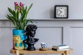 Minimalist living room interior with wooden console, beautiful plants in hipster pot, leaf, book, clock, shelf, decoration.