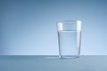 Minimalist photo of a glass of clean drinking water on blue background