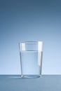 Minimalist photo of a glass of clean drinking water on blue background
