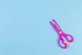 Minimalist photo of pink children`s scissors on blue background