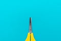 Minimalist photo of yellow children`s scissors on the turquoise blue background