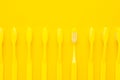 Minimalist photo of yellow toothbrushes turned down and one of them turned up