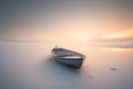 Minimalist picture of a small boat on a partially frozen lake. Winter landscape with sunset.