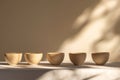 Minimalist row of ceramic cups in soft natural light and shadows Royalty Free Stock Photo