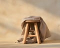 Minimalist Rustic Still Life: Natural Wood Stool with Draped Linen Cloth in Soft Sunlight Royalty Free Stock Photo