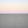 A minimalist scene featuring a smooth, light gray concrete wall with subtle surface cracks and four Royalty Free Stock Photo