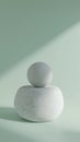 Minimalist sculpture featuring a smooth sphere balancing on a textured stone against a soft green background. The composition Royalty Free Stock Photo