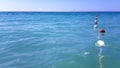 Minimalist seascape with red and white buoys on the nautical rope in the calm sea water