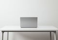 A minimalist setup features a closed silver laptop placed centrally on a plain white Royalty Free Stock Photo