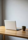 A minimalist setup features an open laptop and a ceramic mug on a light wooden Royalty Free Stock Photo