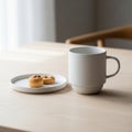 A minimalist setup on a light wooden table features a plain white ceramic mug and a small round Royalty Free Stock Photo