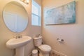 Minimalist small bathroom interior with toilet pedestal sink and round mirror