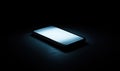 Minimalist smartphone illuminated in dark environment showcasing sleek design and modern technology Royalty Free Stock Photo
