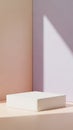Minimalist square white podium with soft pastel pink and lavender walls in a studio setting with diffused light and gentle shadow Royalty Free Stock Photo