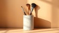 Minimalist still life featuring makeup brushes in a white ceramic container on a neutral backdrop. Royalty Free Stock Photo