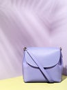 Single trendy purple crossbody handbag with tropic leaves shadow overlay.