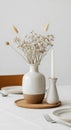 A minimalist table setting features a white ceramic vase with a brown base holding Royalty Free Stock Photo