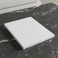 A minimalist white book rests on a black marble table with visible white veining. The Royalty Free Stock Photo