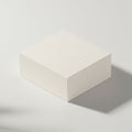 A minimalist white cardboard box with a square shape sits on a light surface. The box Royalty Free Stock Photo