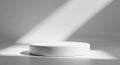 Minimalist white cylindrical podium with dramatic diagonal light and shadow casting across a clean gray background Royalty Free Stock Photo