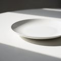 Minimalist White Plate Casting Shadows on a White Surface Under Natural Light dish ceramic Royalty Free Stock Photo