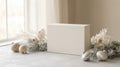 A minimalist white rectangular box sits on a textured surface surrounded by soft focus winter-themed decorations Royalty Free Stock Photo