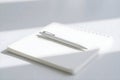 A minimalist white scene featuring a pen resting on top of a closed notebook in soft light setting Royalty Free Stock Photo