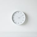 Minimalist white wall clock with black hour markers and hands. Circular shape with a Royalty Free Stock Photo