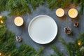 Minimalist winter table setting with pine branches, candles, and pinecones Royalty Free Stock Photo