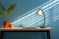 Minimalist workplace, a table with lamp, plant, and handles on blue