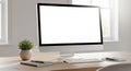 Minimalist workspace featuring computer with blank white screen and plant Royalty Free Stock Photo